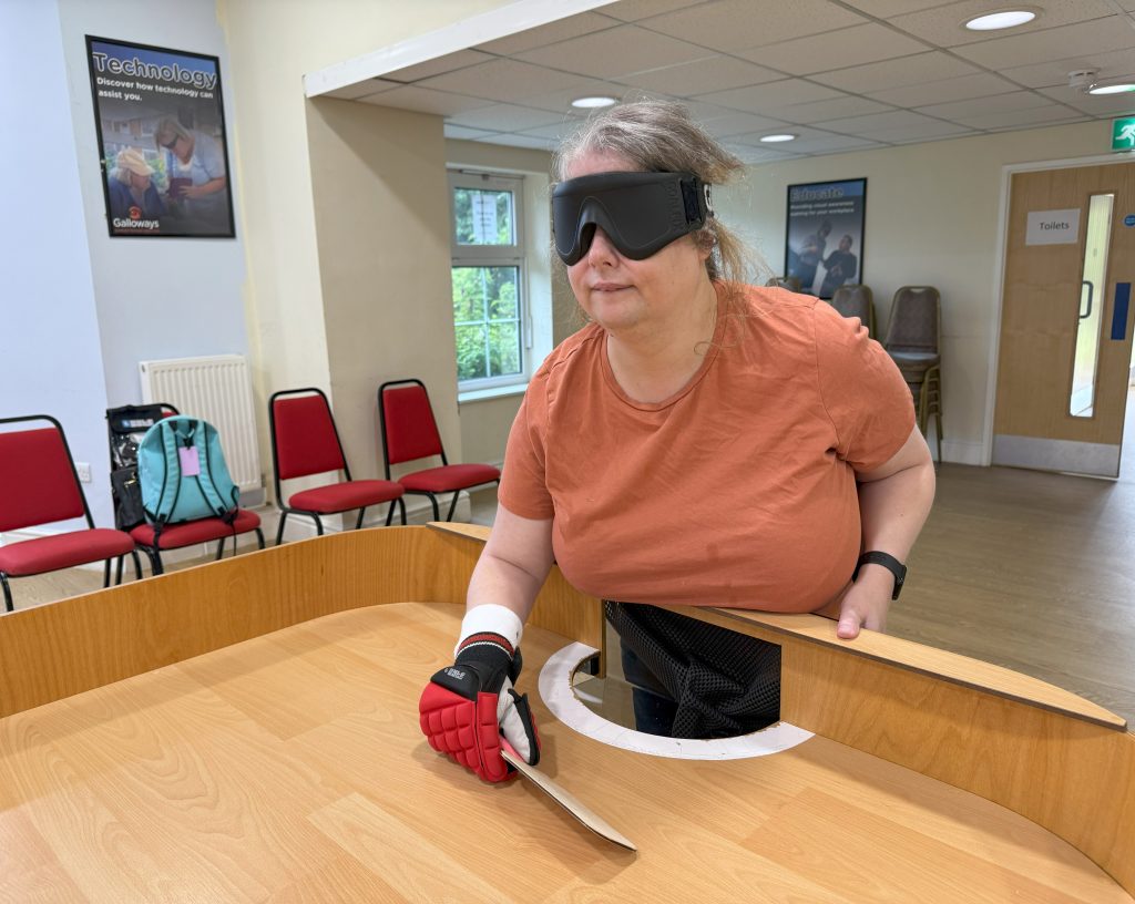 Kara at the end of a showdown table with her bat in a defensive position in front of the goal area waiting for her opponent to serve