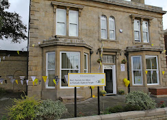 Photo of the outside of Bury Blind Society, the outside of the building is decorated with yellow balloons and yellow and white bunting